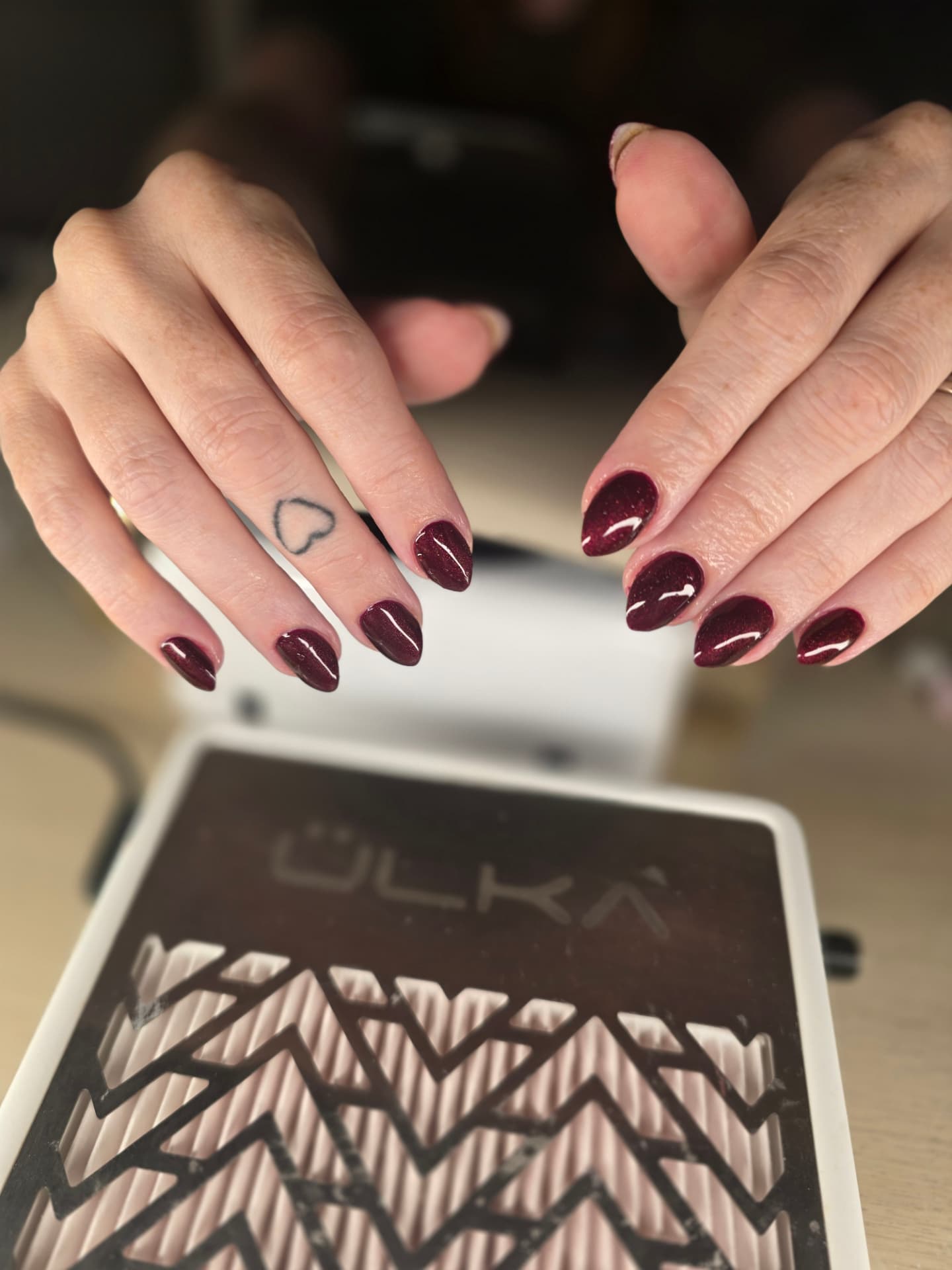 A finished burgundy UV/LED gel polish manicure at AuraLuxe Beauty Studio