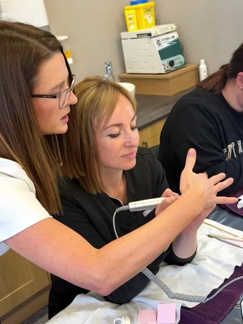 Alexis guiding a learner's e-file hand position at AuraLuxe Academy in Midleton
