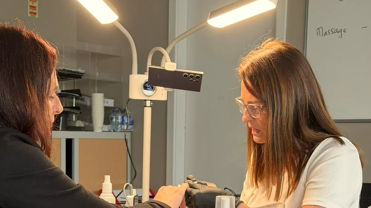 Alexis teaching at a nail station at Cork ETB, with a whiteboard behind her